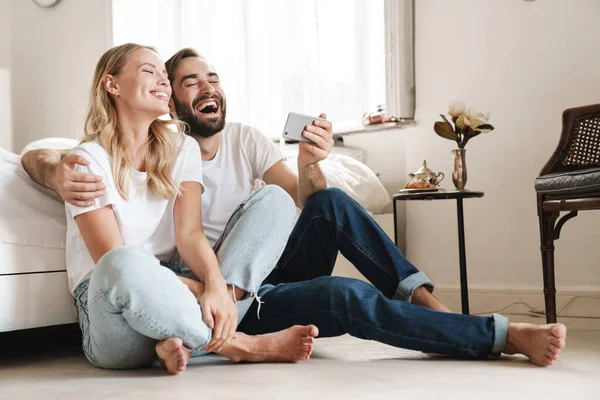 Kanepede oturan neşeli, güzel genç çift.