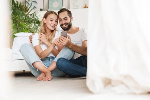 Alegre belo casal jovem sentado no sofá — Fotografia de Stock