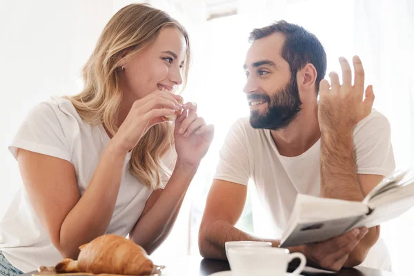 Happy beautiful young couple having breakfast at the kitchen table — Stock Photo, Image