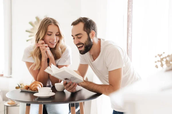 Feliz hermosa pareja joven desayunando en la mesa de la cocina — Foto de Stock