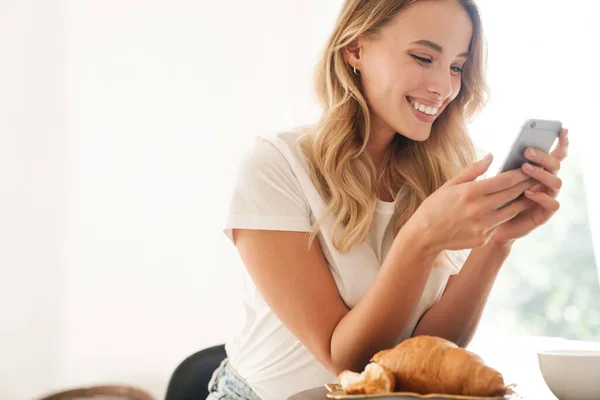 Привлекательная молодая улыбающаяся женщина с помощью мобильного телефона — стоковое фото
