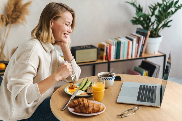 Fénykép boldog szőke nő használja laptop reggeli közben — Stock Fotó