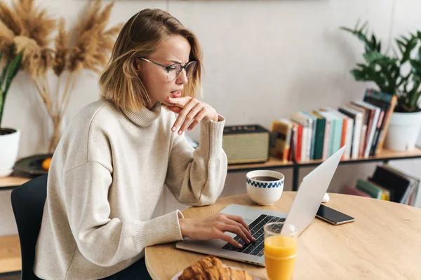 Fénykép zavarodott nő használja laptop reggeli közben — Stock Fotó