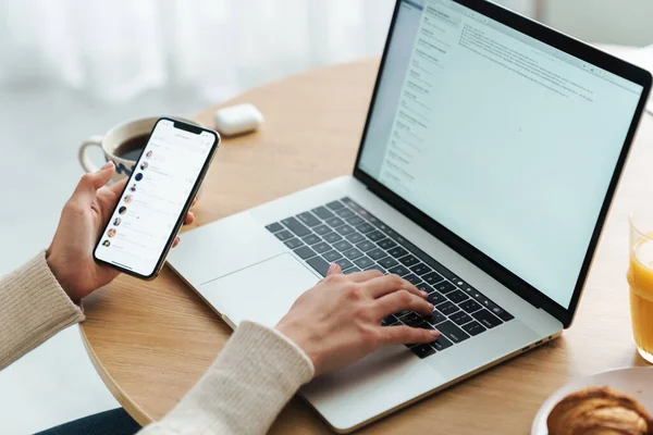 Cropped photo of young caucasian woman typing on laptop and cellphone — 스톡 사진