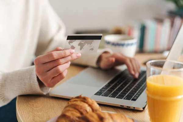 Обрізана фотографія молодої жінки, що тримає кредитну картку і використовує ноутбук — стокове фото