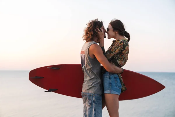 Feliz joven pareja abrazándose mientras está de pie en la playa —  Fotos de Stock