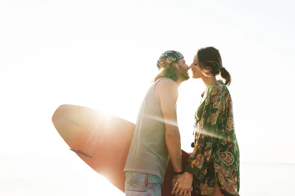 Foto de pareja romántica agradable sosteniendo tabla de surf y besándose —  Fotos de Stock