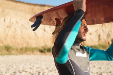 Sörf tahtası tutan sakallı bir adamın fotoğrafı.