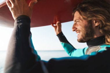 Kafasında yakışıklı, gülümseyen bir sörf tahtası resmi.