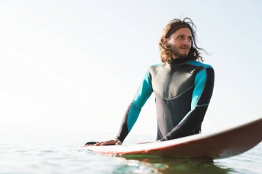 Sörf yaparken sörf tahtası kullanan yakışıklı bir erkeğin fotoğrafı.