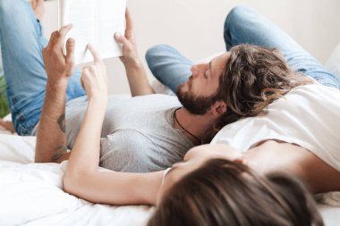 Evde birbirini seven bir çift birlikte kitap okuyor..