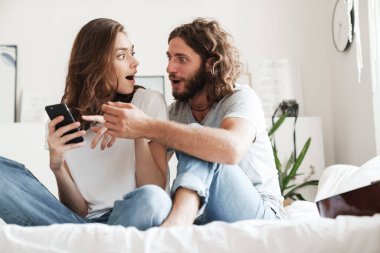 Cep telefonu kullanan sevimli genç çift.