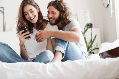 Cep telefonu kullanan sevimli genç çift.