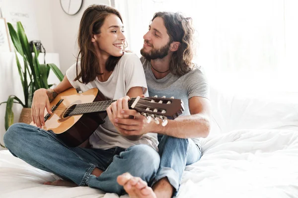 Loving couple indoors at home play on guitar. — 스톡 사진