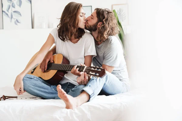 Loving couple indoors at home play on guitar. — 스톡 사진