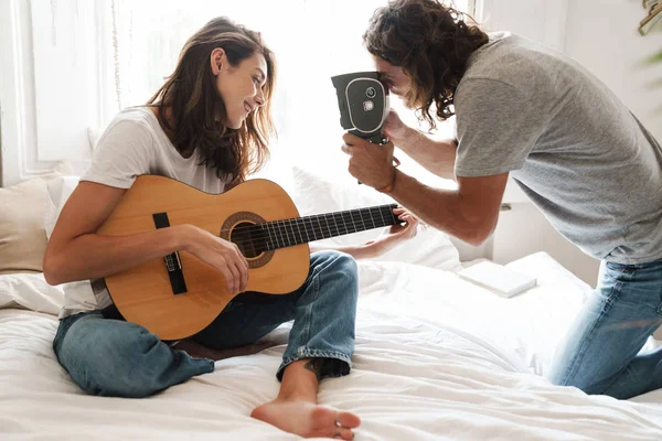 Couple indoors at home sit on bed play on guitar — 스톡 사진