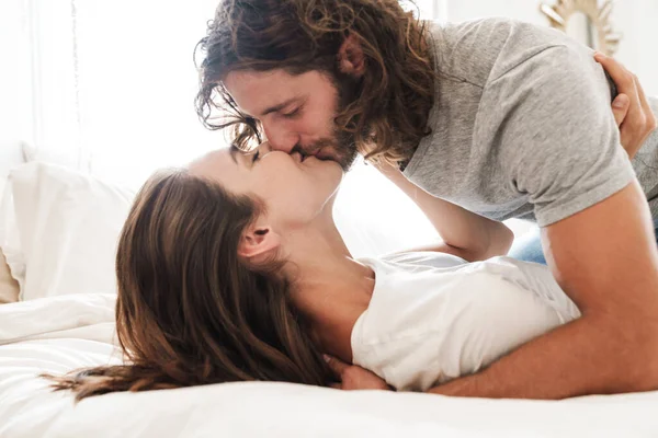 Aimer couple à l'intérieur à la maison se trouve sur le lit baisers . — Photo