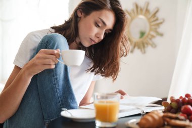 Evdeki masada oturan kadın kahvaltı yapıyor.