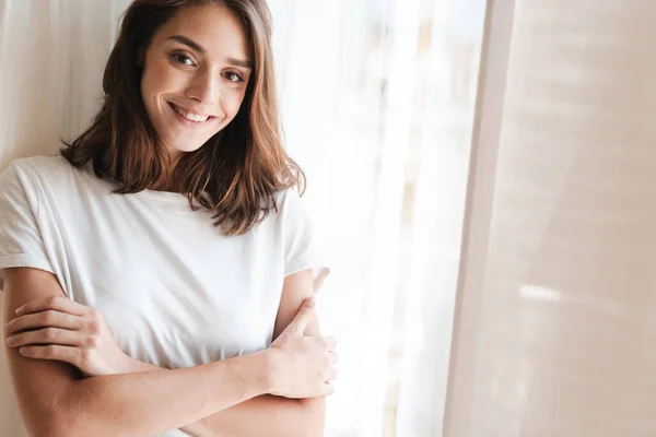 Joven mujer alegre en casa posando cerca de la ventana . — Foto de Stock