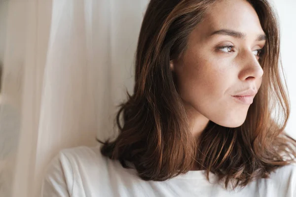 Vrouw binnen thuis poseren in de buurt van raam. — Stockfoto