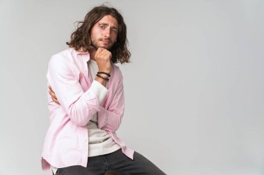 Yakışıklı, düşünceli, sıradan kıyafetler giyen genç adam.