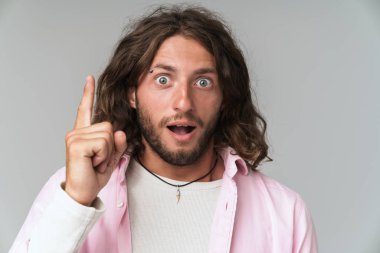 Rahat giyinen heyecanlı genç adam ayakta.