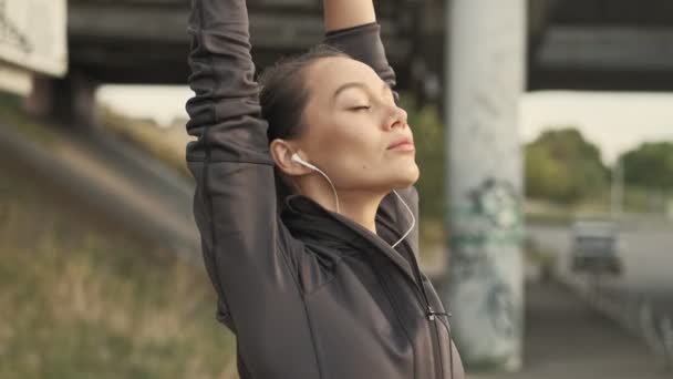 Kulaklıklı Kollarını Dışarı Uzatmış Sakin Asyalı Güzel Bir Spor Kadının — Stok video
