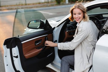 Image of young beautiful businesslike woman sitting in luxury ca