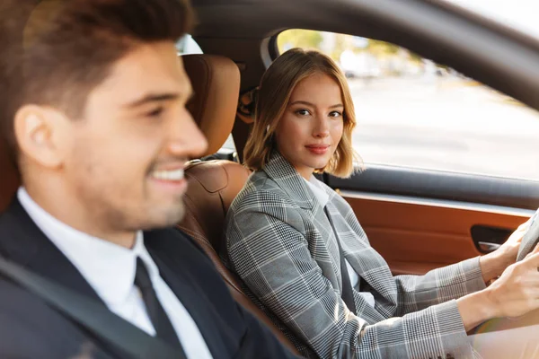 Image of young caucasian businesslike man and woman riding in ca — Stockfoto