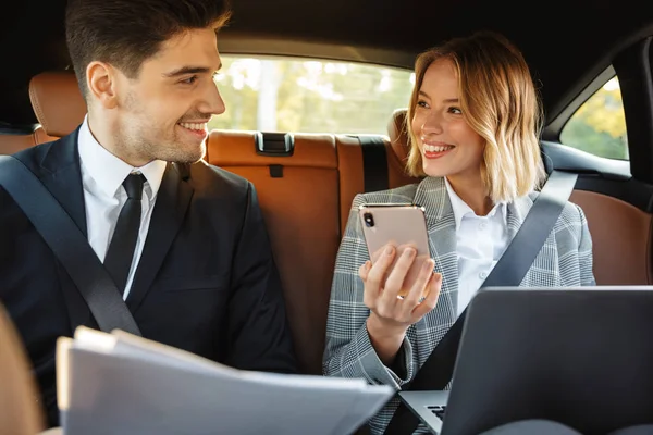 Image of businesslike man and woman sitting in car with working — Stockfoto