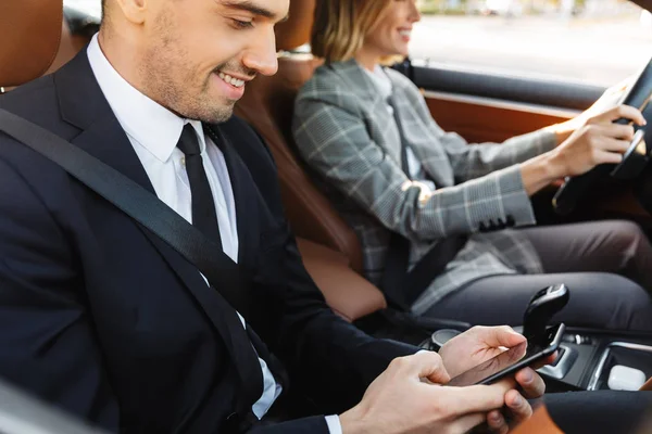 Image of young caucasian businesslike man and woman riding in ca — Stockfoto