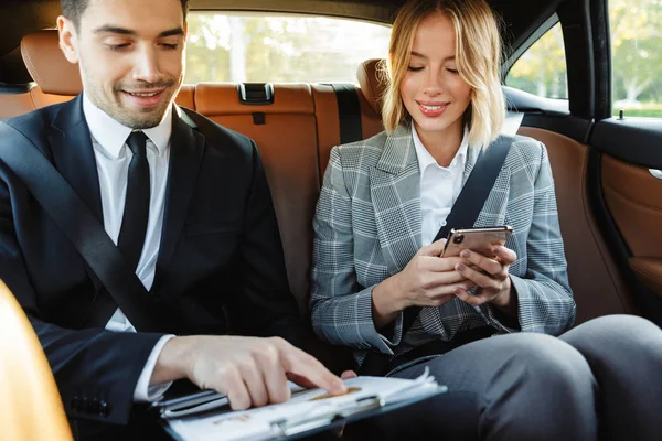 Immagine di uomo e donna d'affari seduti in macchina con il lavoro — Foto Stock