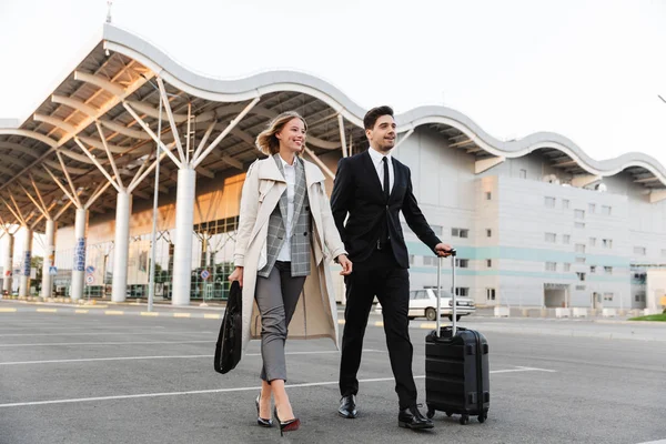 Photo of smiling colleagues man and woman walking with suitcase — 스톡 사진