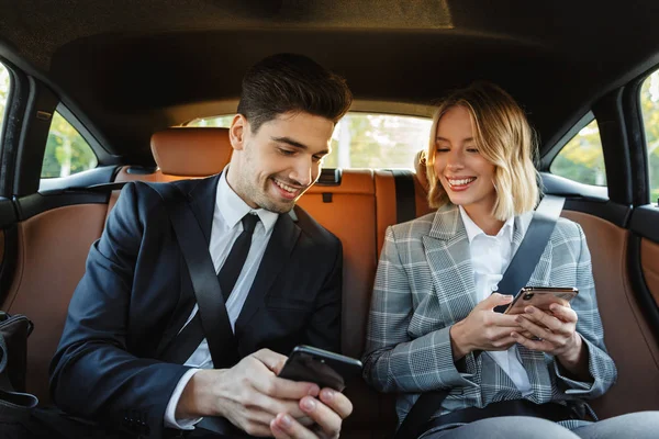 Image of young businesslike man and woman using smartphones in c — 스톡 사진