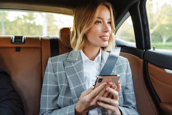 Image of young businesslike woman sitting inside car and using c — Stok fotoğraf