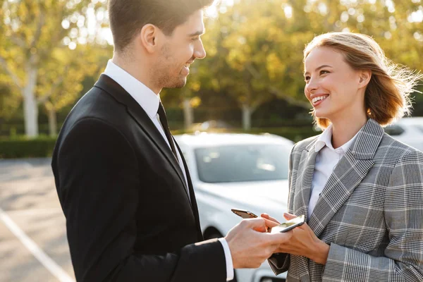 Photo of smiling man and woman talking and using cellphones — Stok fotoğraf