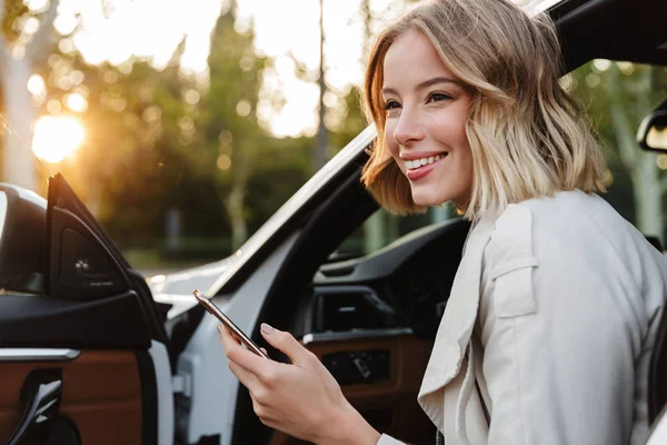 Imagen de hermosa mujer de negocios sentada en el coche y usando c — Foto de Stock