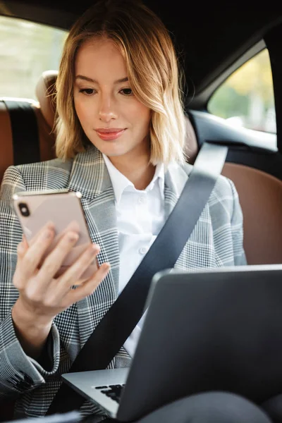 Imagen de una joven mujer de negocios usando teléfonos celulares y portátiles —  Fotos de Stock