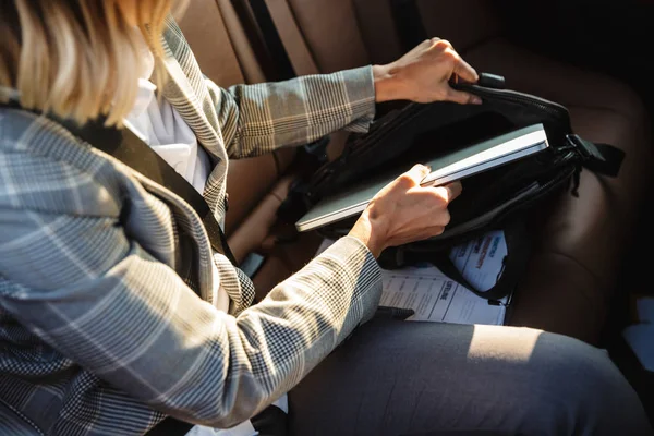 Abgeschnittenes Foto einer Geschäftsfrau mit Tasche und Laptop im Auto — Stockfoto