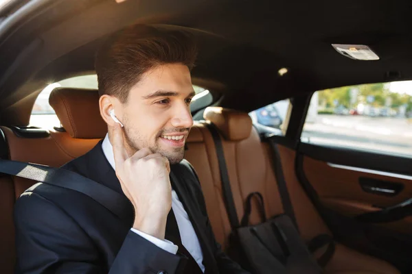 Imagen de joven hombre de negocios caucásico en traje montando en coche — Foto de Stock