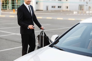 Image of businesslike man opening car with alarm remote key outd