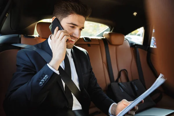Image of young businesslike man in suit talking on cellphone in — ストック写真
