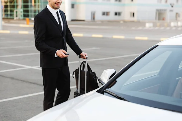 Image of businesslike man opening car with alarm remote key outd — Stockfoto