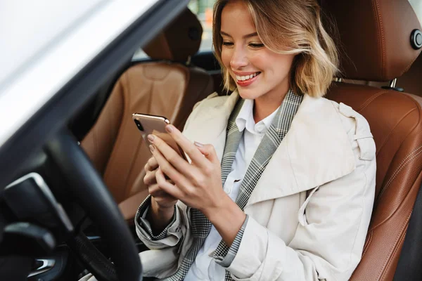 Bild der schönen geschäftstüchtigen Frau, die im Auto sitzt und c benutzt — Stockfoto