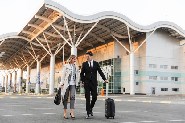 Photo of smiling colleagues man and woman walking with suitcase — Stockfoto