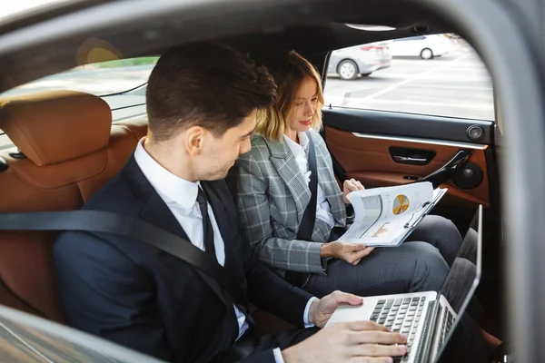 Photo of pleased man and woman working with documents and laptop — Stok fotoğraf