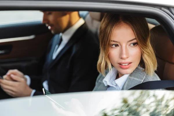 Photo of young blonde businesswoman looking at window while going in car — Stock Photo, Image