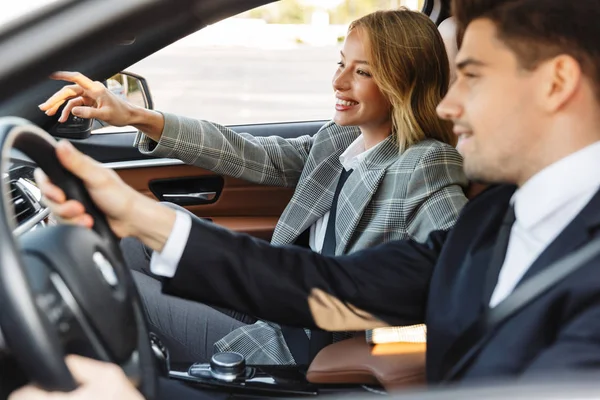 Photo of pleased man and woman talking and smiling while driving in car — Stockfoto