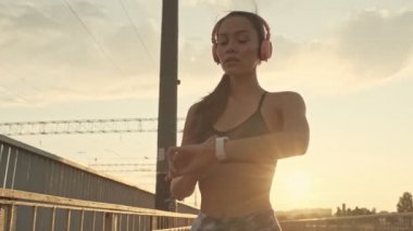 Dışarıda antrenman yaptıktan sonra kol saatini kullanarak kulaklık takan Asyalı güzel ve sakin bir kadın.