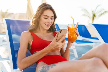 Photo of young cheerful woman sing cellphone and drinking juice